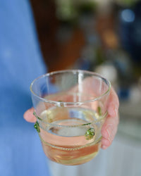 Hand holding a glass with a colorful drink against a blurred background