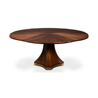A round wooden dining table with a polished pedestal base, featuring a warm brown wood grain finish and subtle brass hardware accents, shown on a white background.