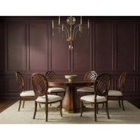 A six-piece dining set featuring a round dark wood table and matching chairs with cream upholstered seats and oval backrests, arranged on a textured rug in front of a dark wood paneled wall under a brass chandelier.