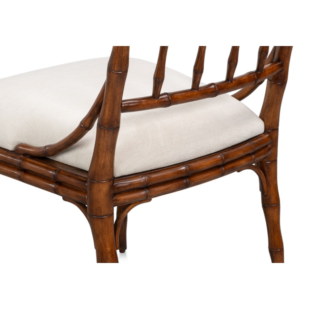A close-up of a dining chair with a brown bamboo-look frame and a light beige upholstered seat cushion, shown against a plain white background.