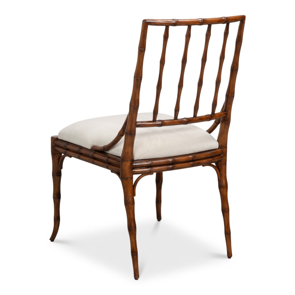 A side dining chair with a brown bamboo-look frame and a light beige upholstered seat cushion, shown from a three-quarter angle on a white background.