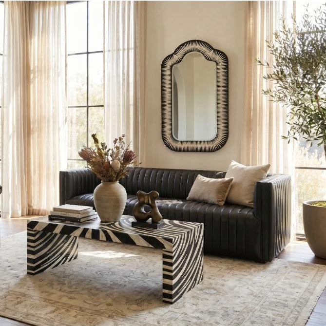 Modern living room with black sofa, armchair, zebra table, and Sarreid's Meridian Bone Inlay Mirror by the windows.