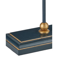 Close-up of a dark navy blue table lamp base with gold trim and a matching gold finial on a white background.