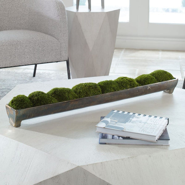 Decorative long planter with green moss on a coffee table in a modern living room.
