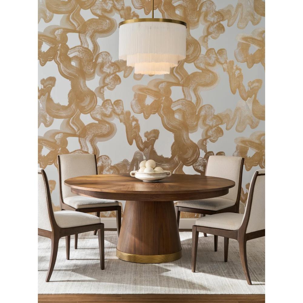 Woodbridge Rawlins Jupe Dining Table with four chairs, a modern chandelier, and gold art make a stunning dining space.