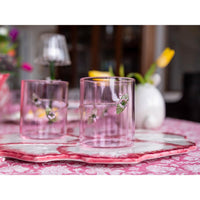 Two Pink Rope + Flower Icon Tumblers by Abigails sit on a pink floral cloth, tulips blooming in the background.