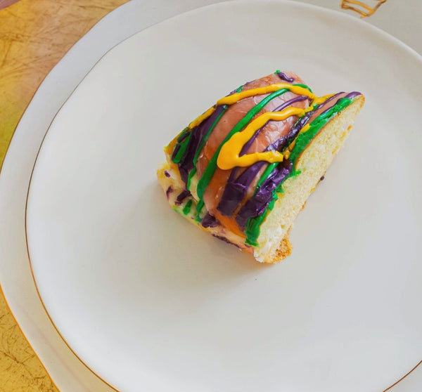 A slice of king cake with colorful icing on an Abigails Gold Rim Salad Plate (set of 2).