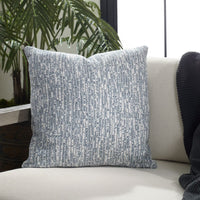 Textured blue pillow on a white couch with a plant in the background