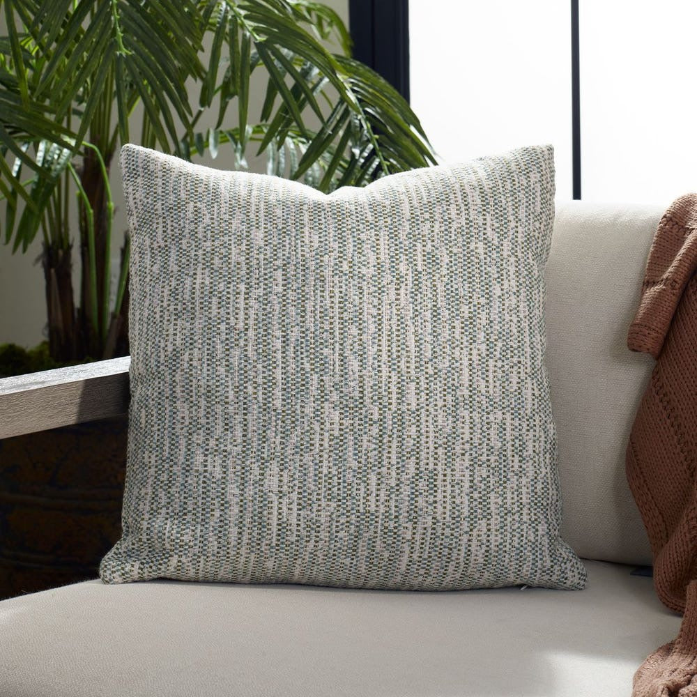 Textured gray pillow on a white couch with plants in the background