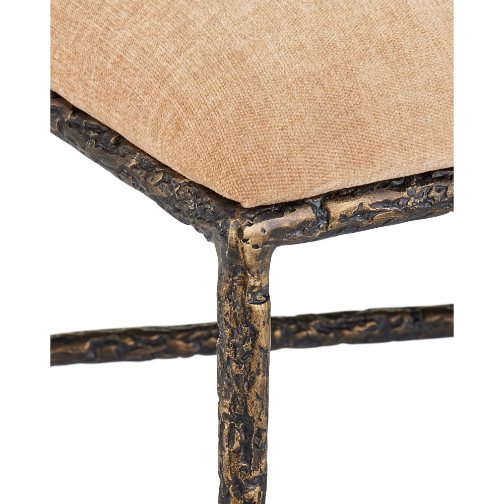 Close-up of a stool or chair corner showing a tan woven fabric cushion on a distressed dark bronze metal frame with a textured, branch-like finish.
