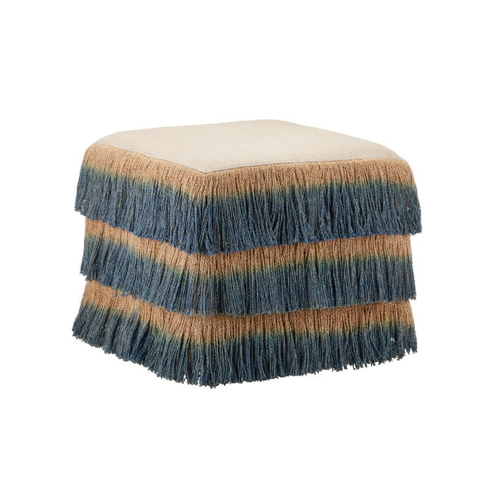 A square upholstered ottoman with tiered fringe. The top cushion is upholstered in a light beige fabric, while the fringed sides feature horizontal stripes of slate blue, tan, and muted green, fading to solid fringe at the bottom.