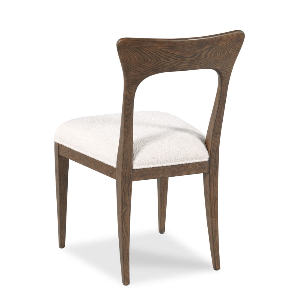 A mid-century modern dining chair with a curved dark brown wooden frame and a white textured bouclé seat cushion, shown from a three-quarter angle on a white background.