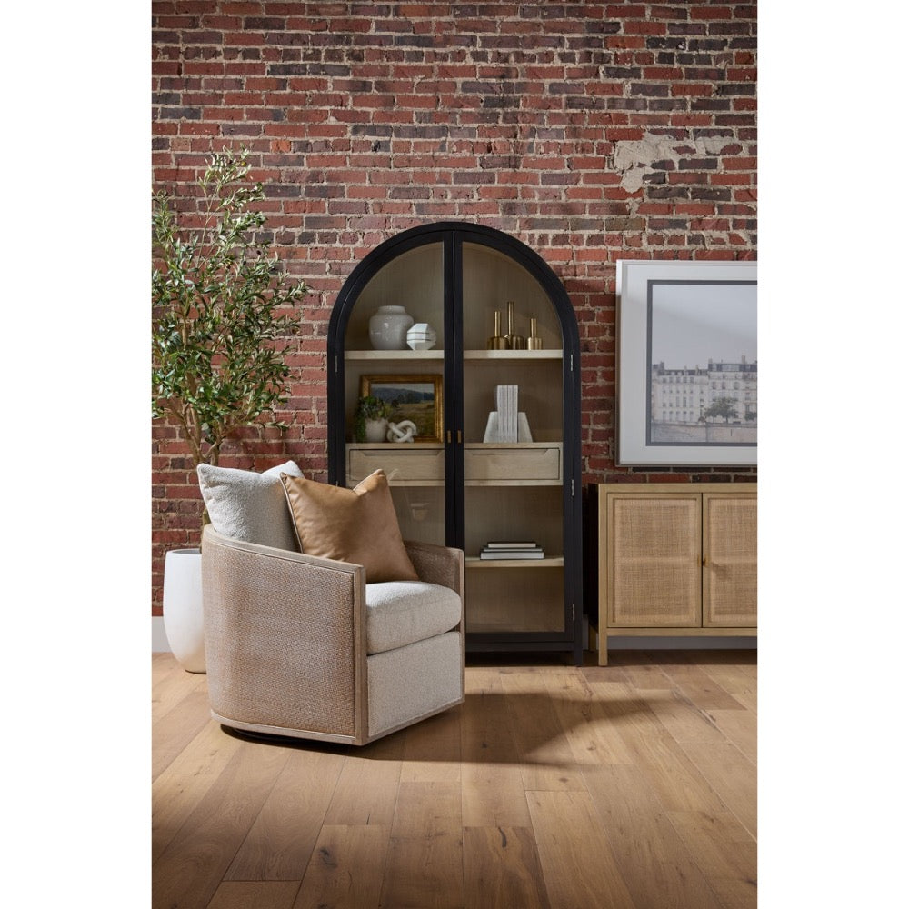 Beige armchair with pillows in a room with a brick wall and bookshelf.