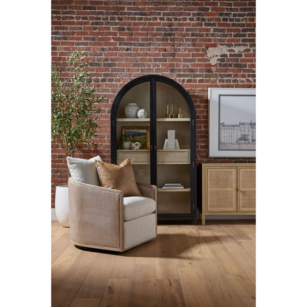 Beige armchair with pillows in a room with a brick wall and bookshelf.
