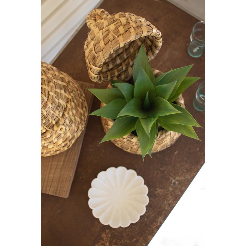 Decorative items including a plant, woven baskets, and a white decorative object on a wooden surface.