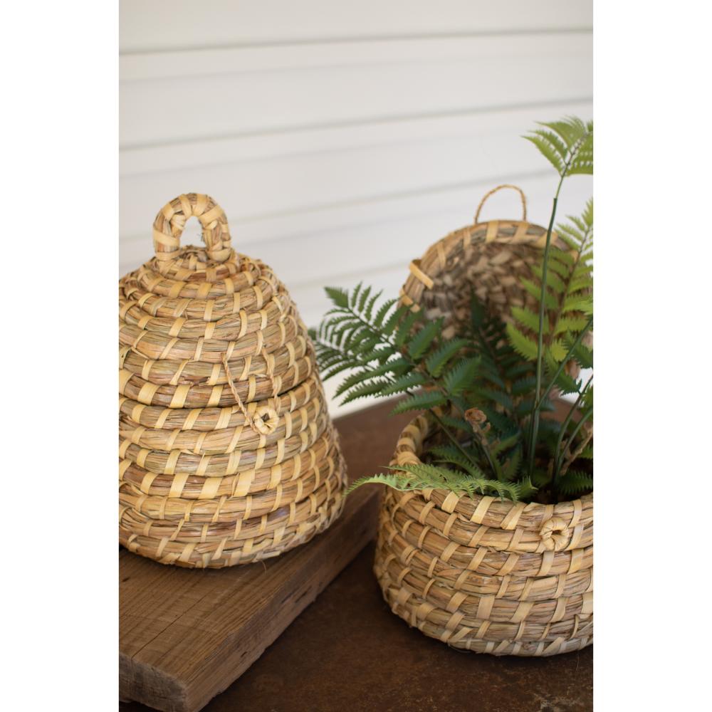 Two woven baskets, one with a handle and the other with planters, on a wooden surface.