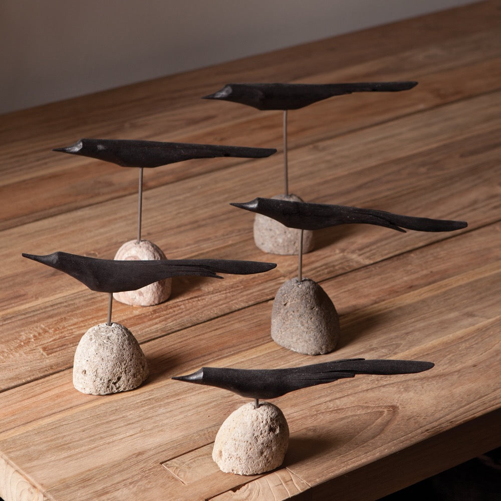 Decorative black birds on stone bases on a wooden surface
