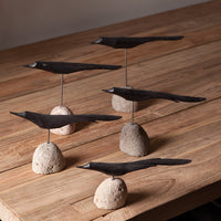 Decorative black birds on stone bases on a wooden surface