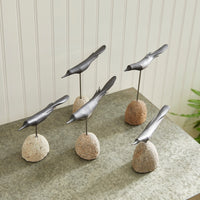 Decorative black bird on stone bases on a table with a neutral background