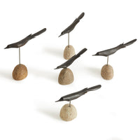 Set of five metal bird sculptures on stone bases against a white background