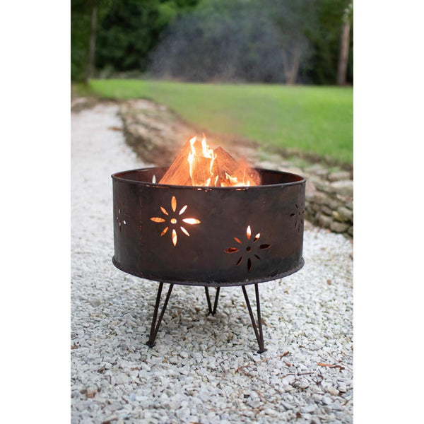 Metal fire pit with flames on a gravel surface in an outdoor setting