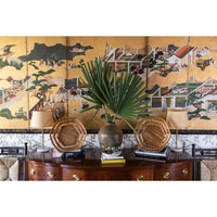 Decorative setting with a vase, baskets, and a plant on a wooden sideboard against a painted wall.