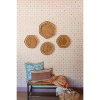 Woven baskets on a wall with colorful pillows on a bench below.