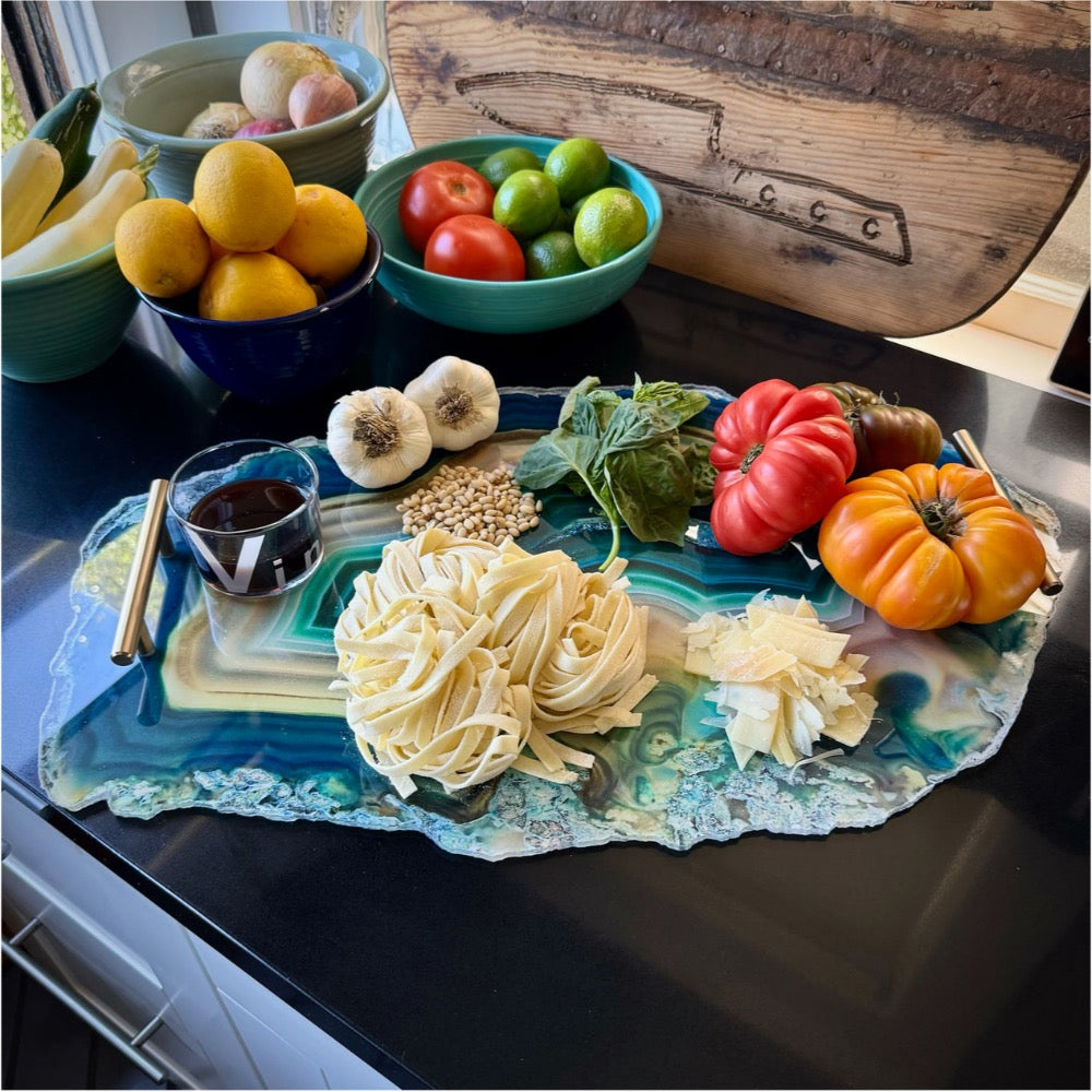 Decorative platter with pasta, vegetables, and a glass of red wine on a kitchen counter.