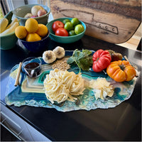 Decorative platter with pasta, vegetables, and a glass of red wine on a kitchen counter.