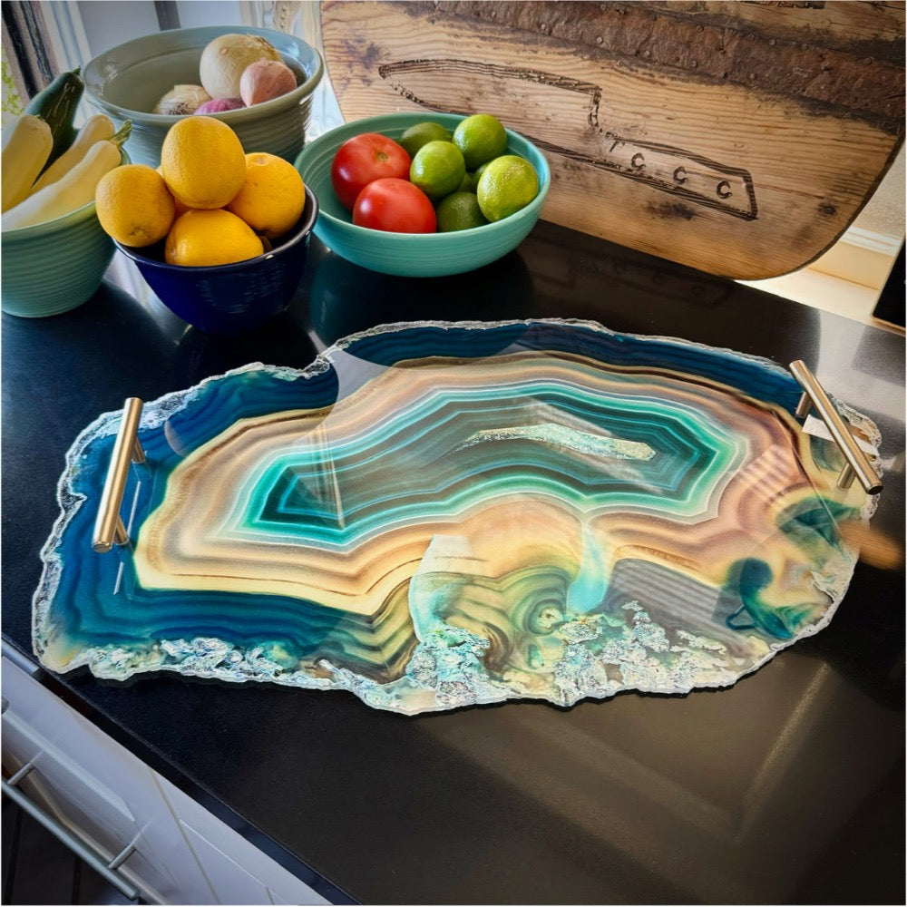 Decorative agate-style serving tray on a kitchen counter with fruit bowls in the background.
