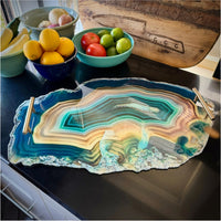 Decorative agate-style serving tray on a kitchen counter with fruit bowls in the background.