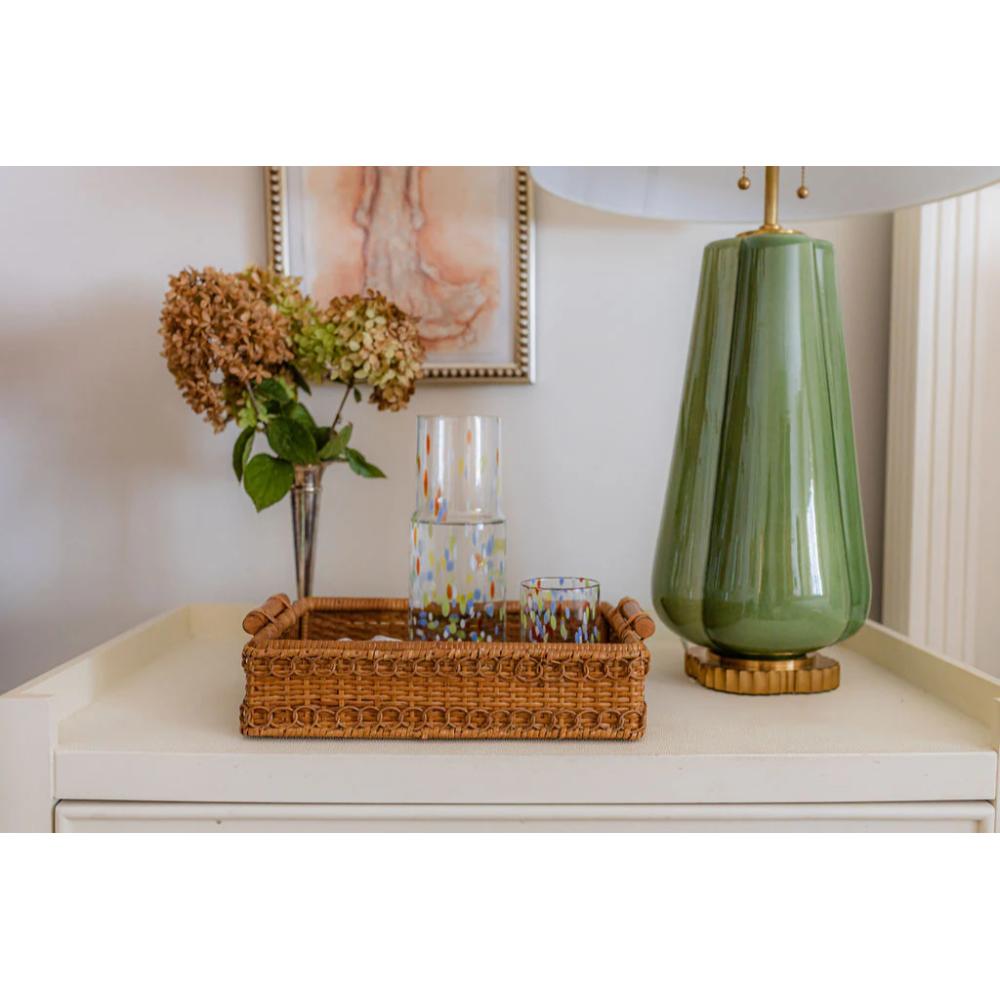 Decorative items on a shelf including a green lamp, wicker basket, and flowers.