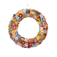 A circular fabric flower wreath made of many colorful sewn fabric flowers in assorted patterns and hues, hanging against a plain white background.