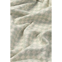 A close-up of a soft, textured fabric with a light sage green and off-white checkerboard pattern, shown with gentle folds.