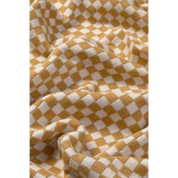 A close-up of a draped fabric with a mustard yellow and off-white checkerboard pattern.