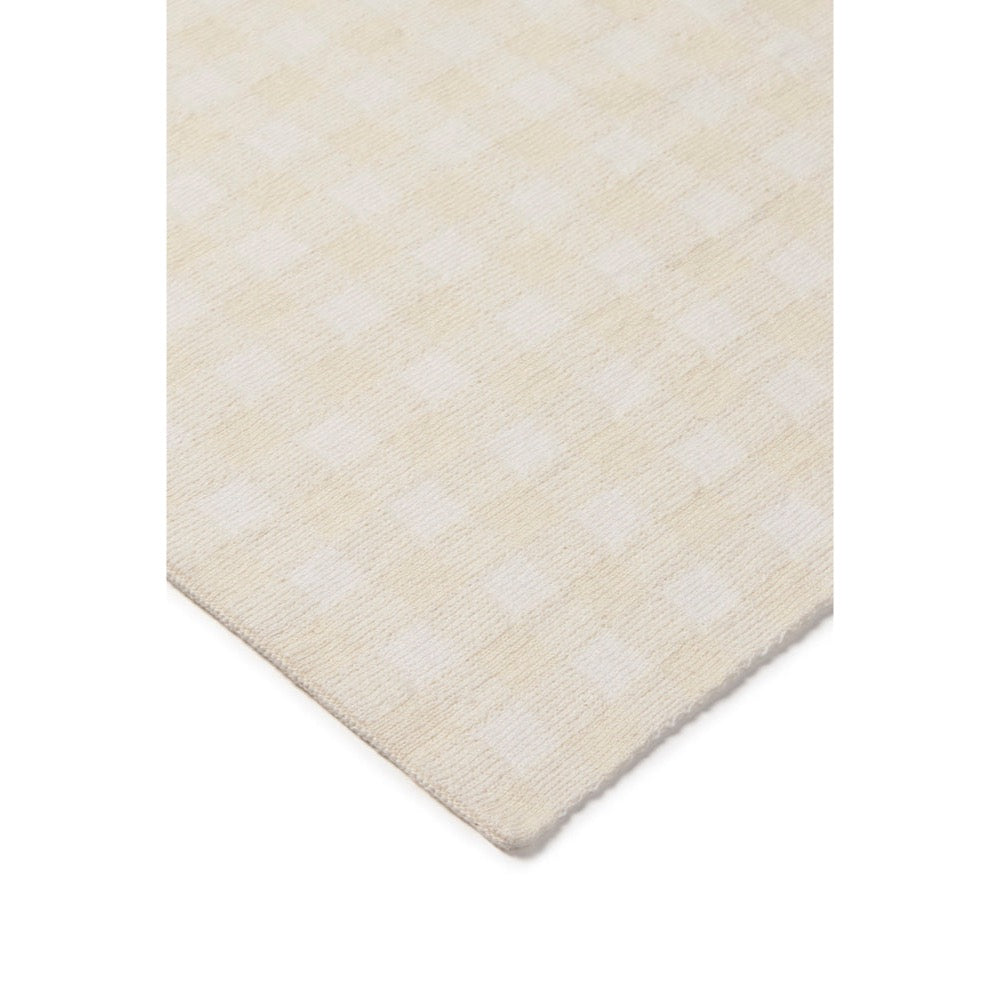 A close-up of a cream and off-white checkered fabric or rug corner, showing the woven texture and pattern against a plain white background.