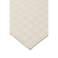 A close-up of a cream and off-white checkered fabric or rug corner, showing the woven texture and pattern against a plain white background.