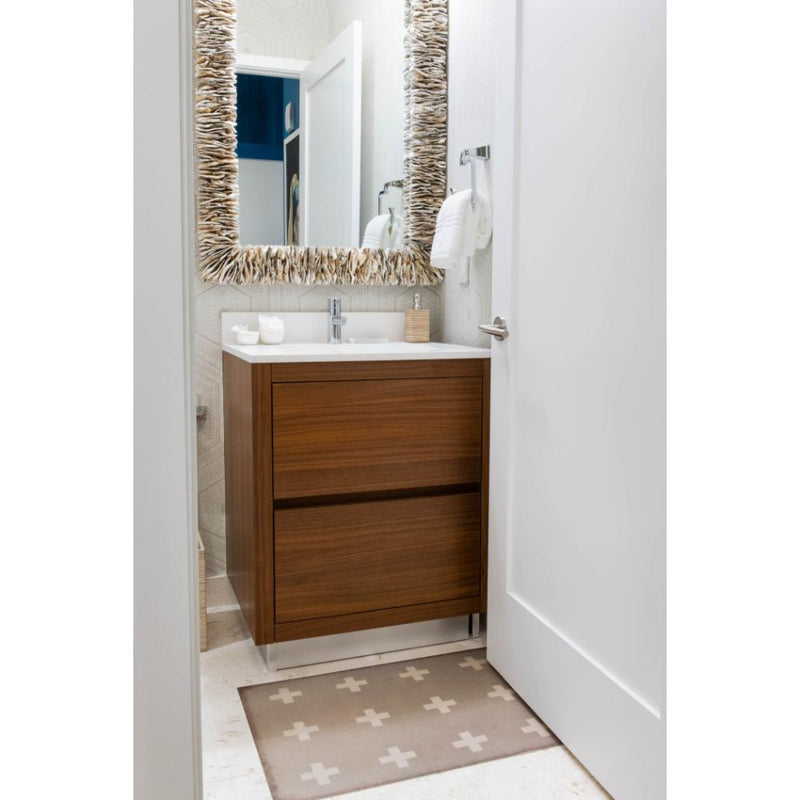 A modern bathroom featuring a wooden vanity, the Mina Oyster Shell Mirror by Made Goods, and a geometric rug exudes a subtle coastal vibe.