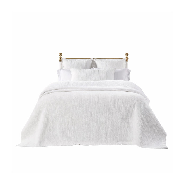 A neatly made bed with the Laela White Bedding Collection by Orchids Lux Home and a brass headboard.