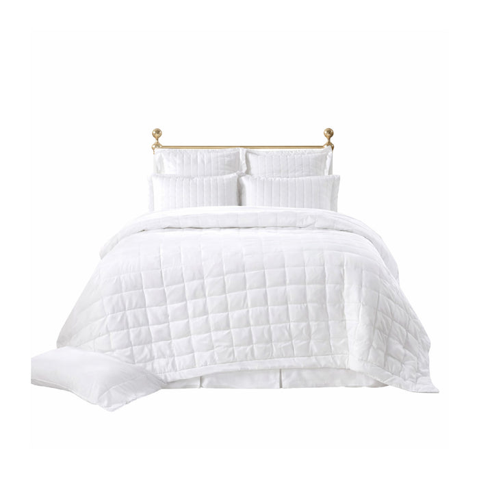 A neatly made bed with the Madison Pearl Bedding Collection by Orchids Lux Home and pearl shams against a gold headboard.