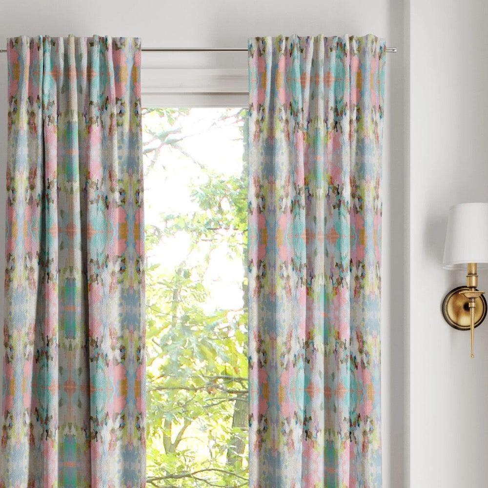 Brooks Avenue Curtain Panels by Laura Park Designs frame the window, with leafy trees outside and a wall sconce nearby.