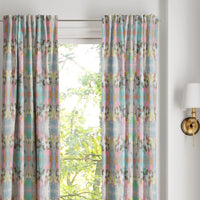 Brooks Avenue Curtain Panels by Laura Park Designs frame the window, with leafy trees outside and a wall sconce nearby.