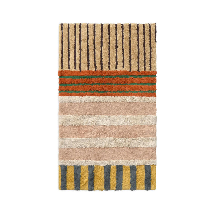 A rectangular shag area rug with a multicolor striped pattern, featuring beige, pink, orange, green, and yellow sections on a white background.