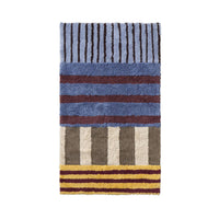 A rectangular shag rug with a multicolor striped pattern, featuring blue, brown, beige, and yellow tones, shown flat against a white background.