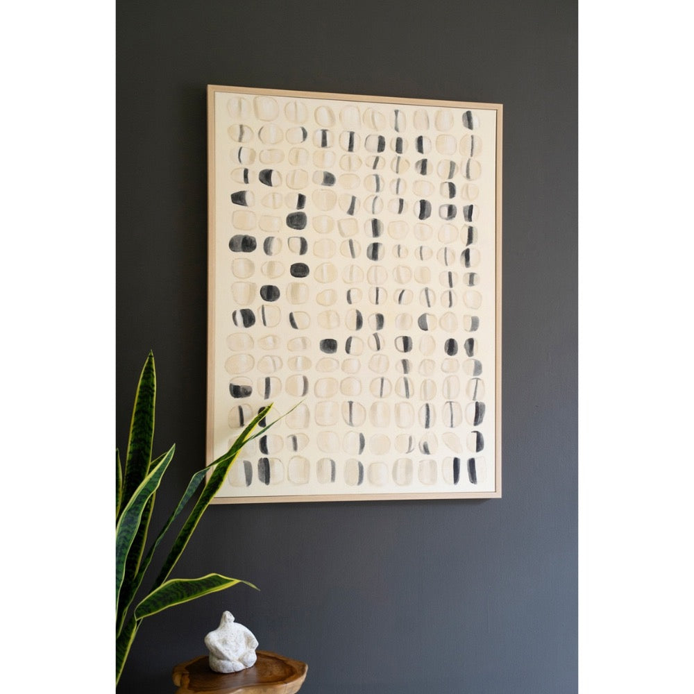 Kalalou's Framed Acrylic Abstract Stones Painting with black/beige circles on a dark wall, next to a plant & sculpture.