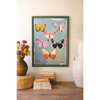 Framed artwork of butterflies on a wall with decorative items below