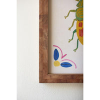 Colorful abstract drawing of a beetle in a wooden frame on a white wall.