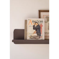 Magazine titled 'The American' on a shelf against a white wall