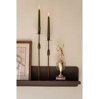 Decorative shelf with candles and a trophy on a neutral wall.