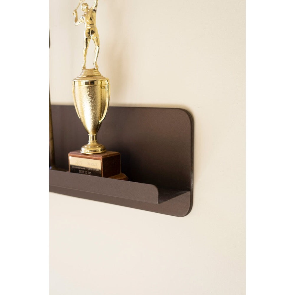 Gold trophy on a dark brown shelf against a beige wall